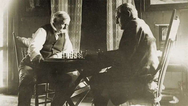 Vintage sepia-toned photo of two men sitting at a table playing chess